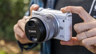 Image shows hands holding the Canon EOS M200 camera.