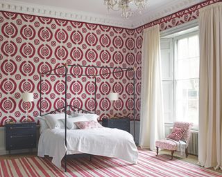 A teenage girl bedroom idea with modern red and white target wallpaper and black four poster bed in period room