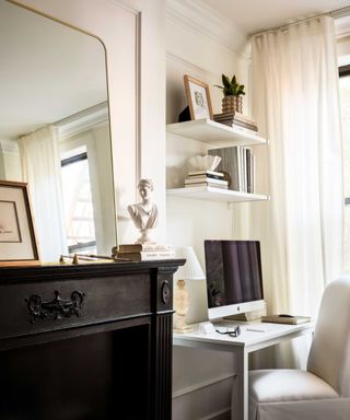 A black fireplace mantel and a small desk setup in a studio apartment