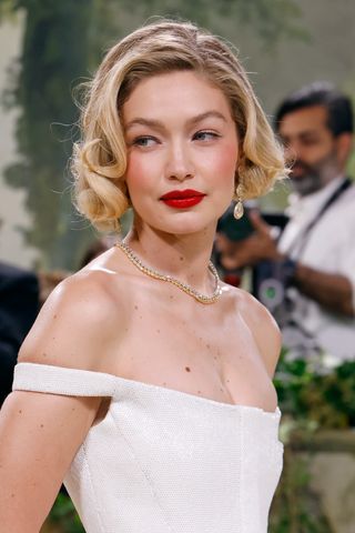 Gigi Hadid with a curly bob hairstyle and red lipstick.