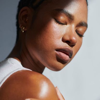 Black woman with eyes closed and glowing skin 