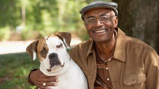 Mature man embracing his bulldog outdoors