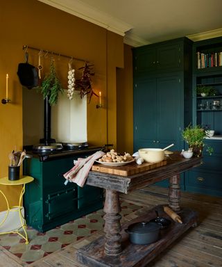 Mustard yellow kitchen with green aga and freestanding work table