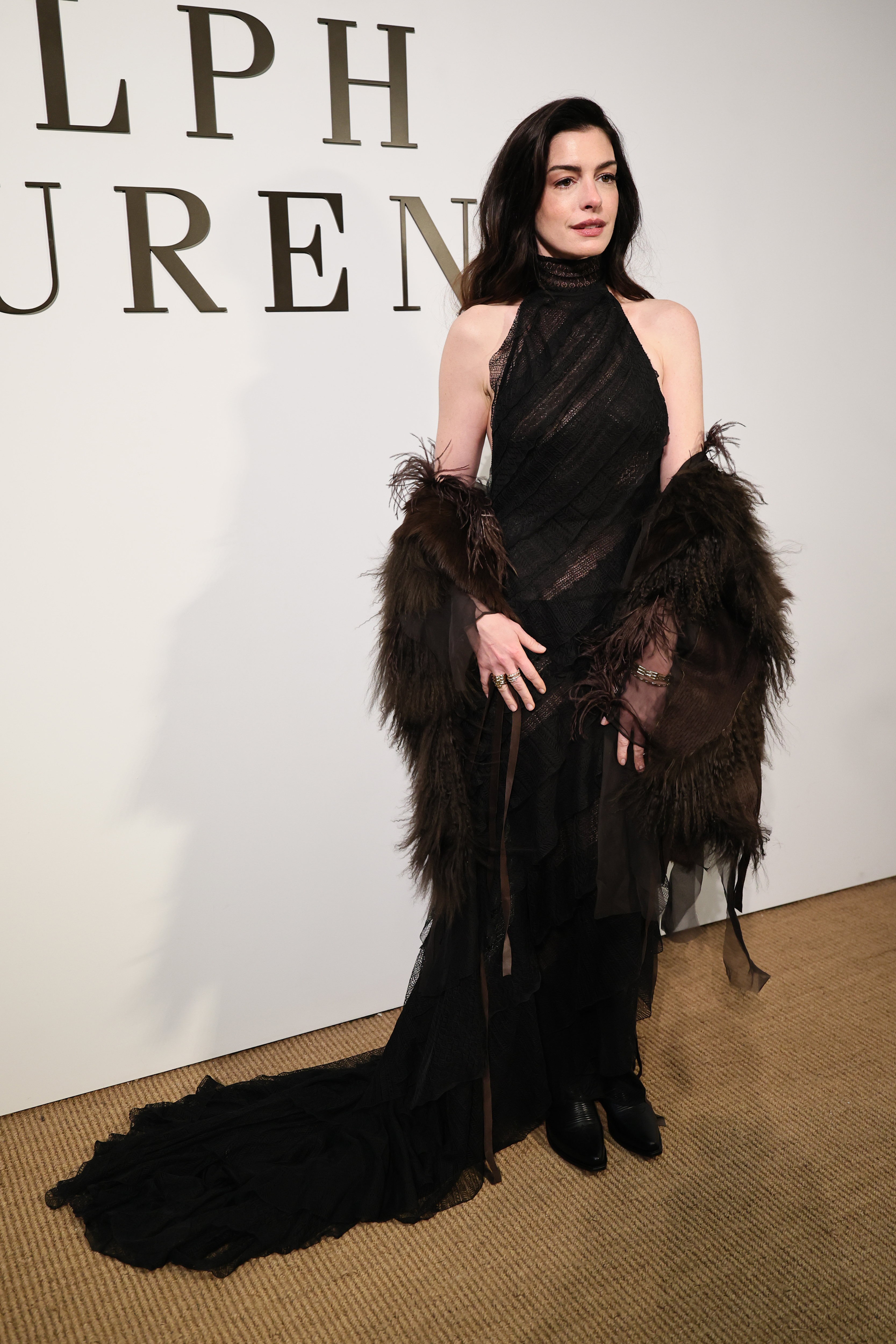 Anne Hathaway arrived at the Ralph Lauren Fall 2026 show in a sheer halter-neck dress and a feather boa