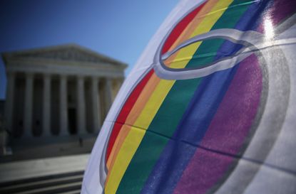 An activist waves a marriage pride flag in front of the Supreme Court.