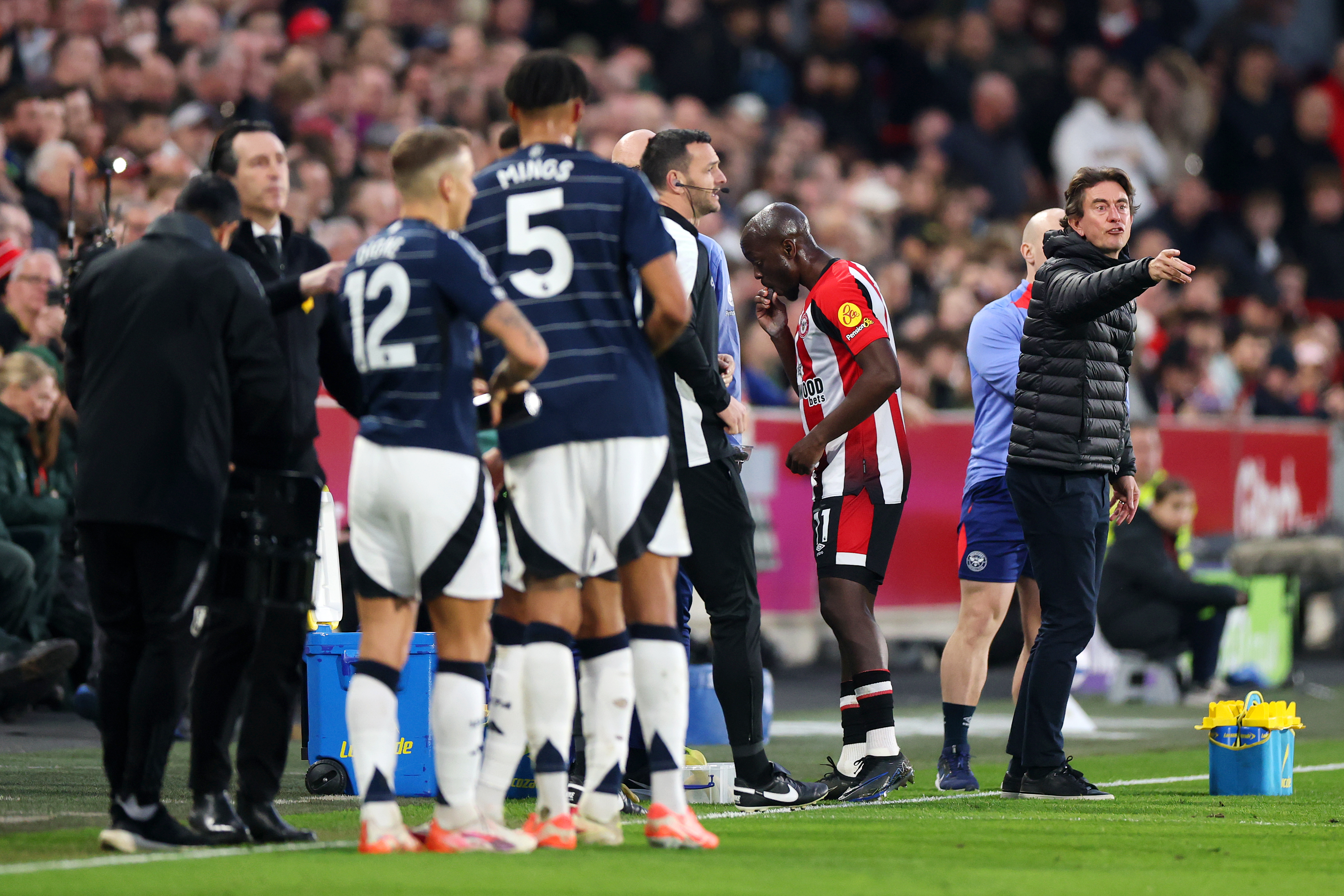 BRENTFORD, ENGLAND - MARCH 08: Thomas Frank, Manager of Brentford, gives the team instructions as Yoane Wissa of Brentford eats a date whilst play is paused to allow muslim players to break their Ramadan fast during the Premier League match between Brentford FC and Aston Villa FC at Brentford Community Stadium on March 08, 2025 in Brentford, England. (Photo by Alex Pantling/Getty Images)