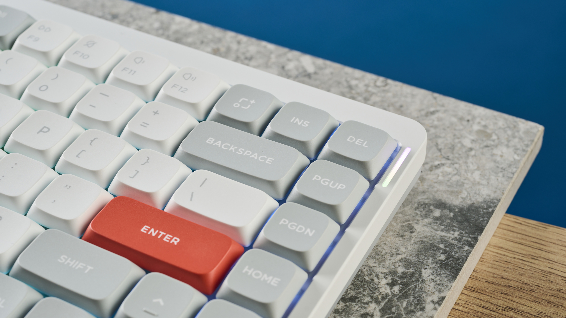A photo of the NuPhy Air75 V2's enter and right-hand keys, on a stone slab with a blue wall in the background.
