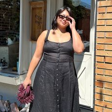 Woman in street wears black dress and sunglasses