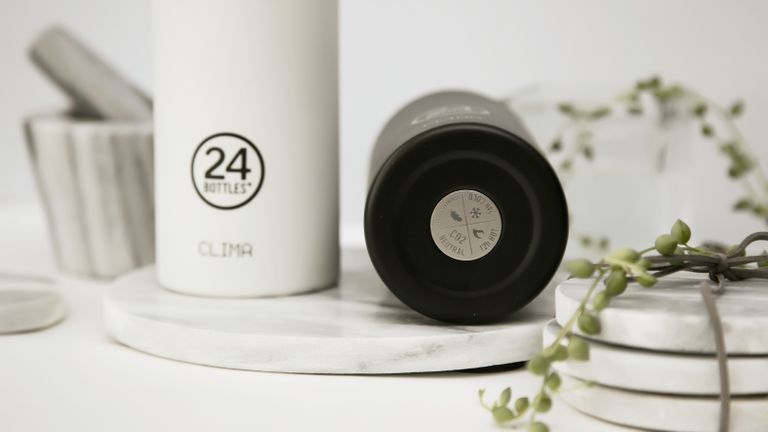 Two of the best water bottles around – one black and one white – on a kitchen counter with coasters and plants