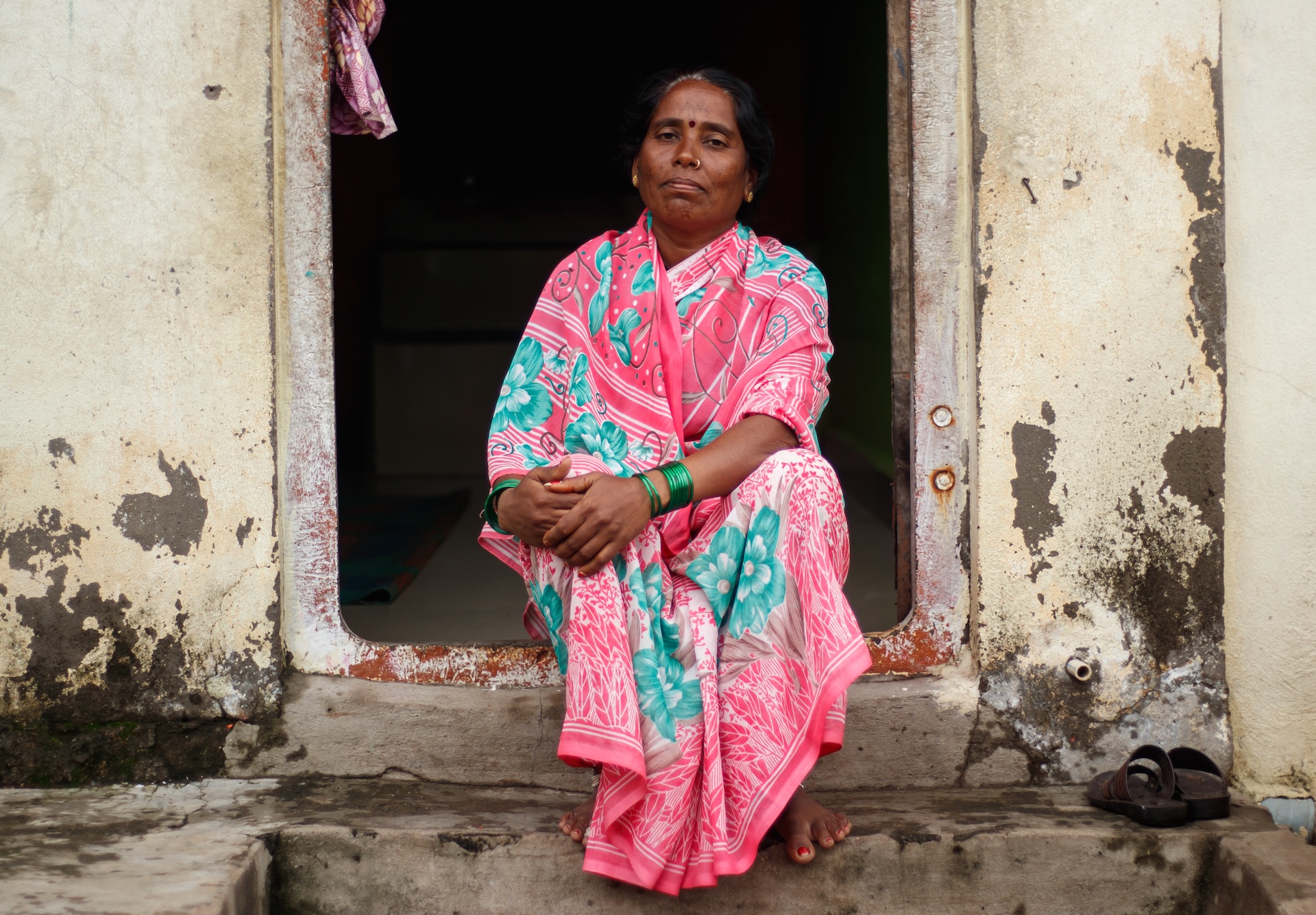a woman in traditional Indian clothing sits in a doorway