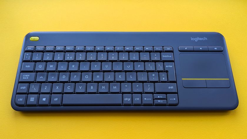 Closeup of Logitech K400 Plus wireless keyboard on a yellow background showing worn keys and buttons