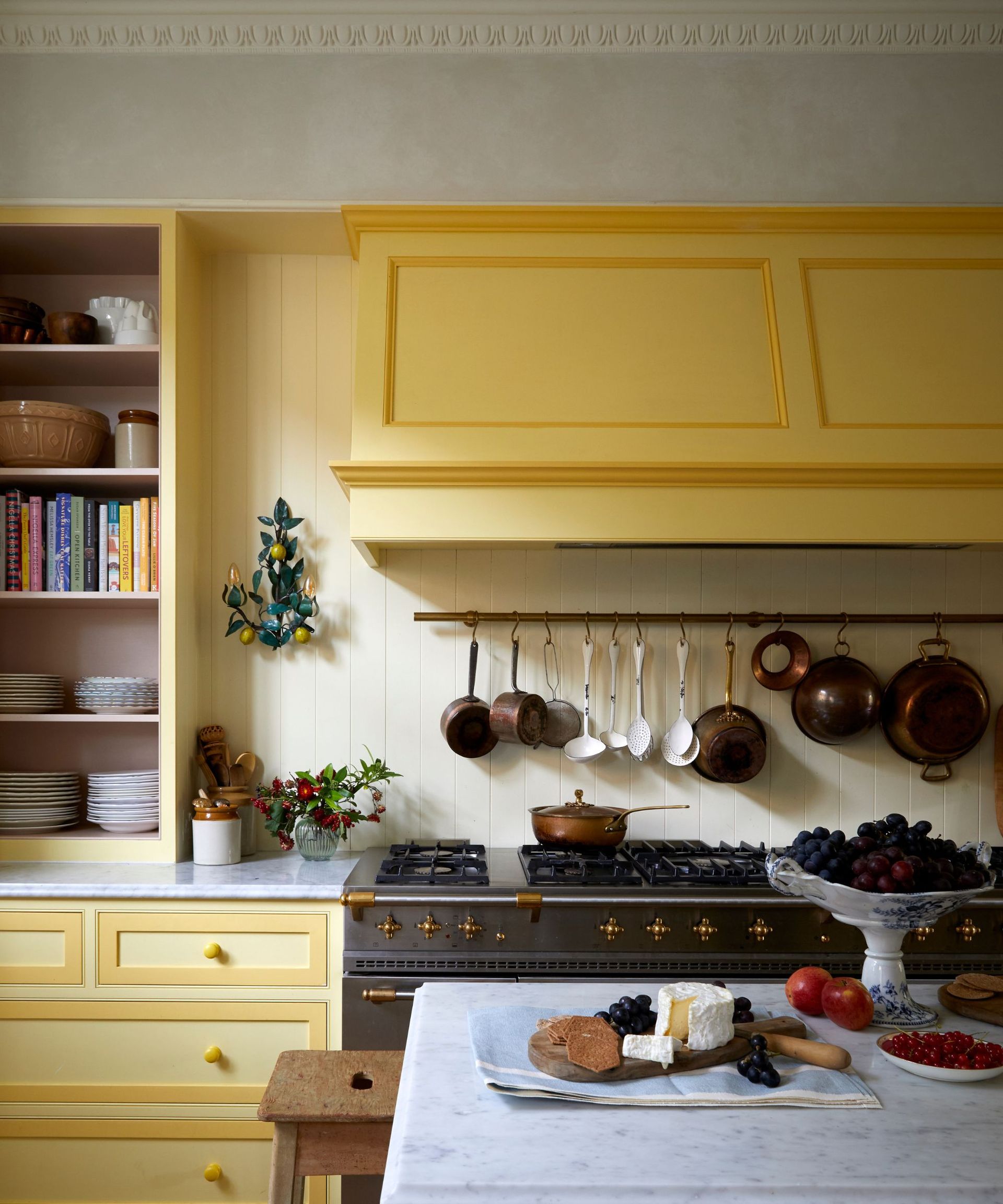 yellow traditional shaker kitchen painted yellow with a large oversized cooker hood