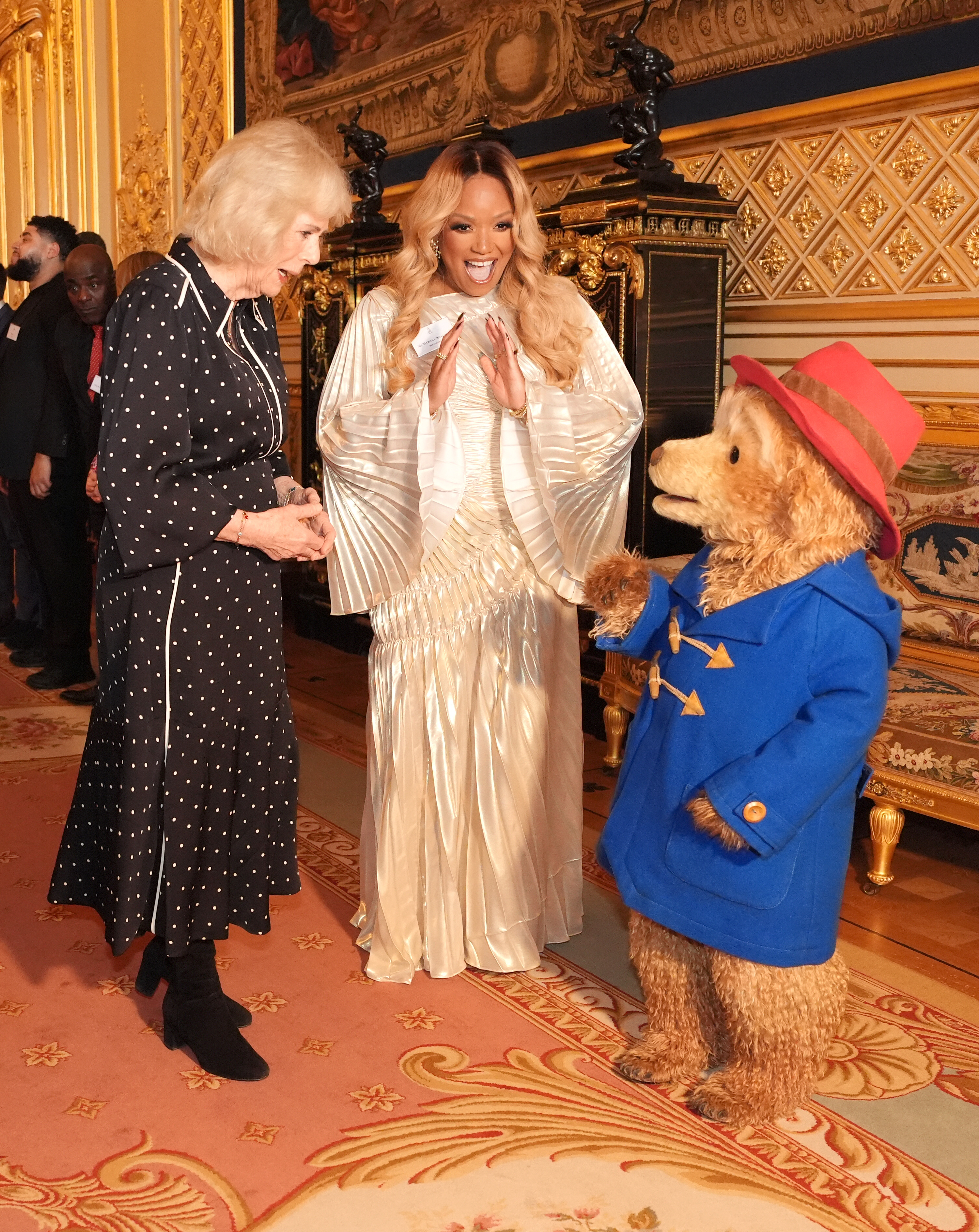 Queen Camilla wearing a polka dot dress talking to Paddington