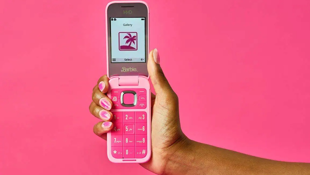 The Barbie flip phone lies open in the hand and displays the gallery app.