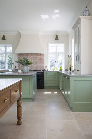 kitchen with white walls and pale green cabinetry and limestone floor