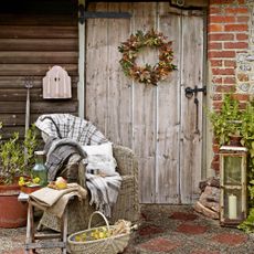 Autumn wreath on a wooden door with wicker chair