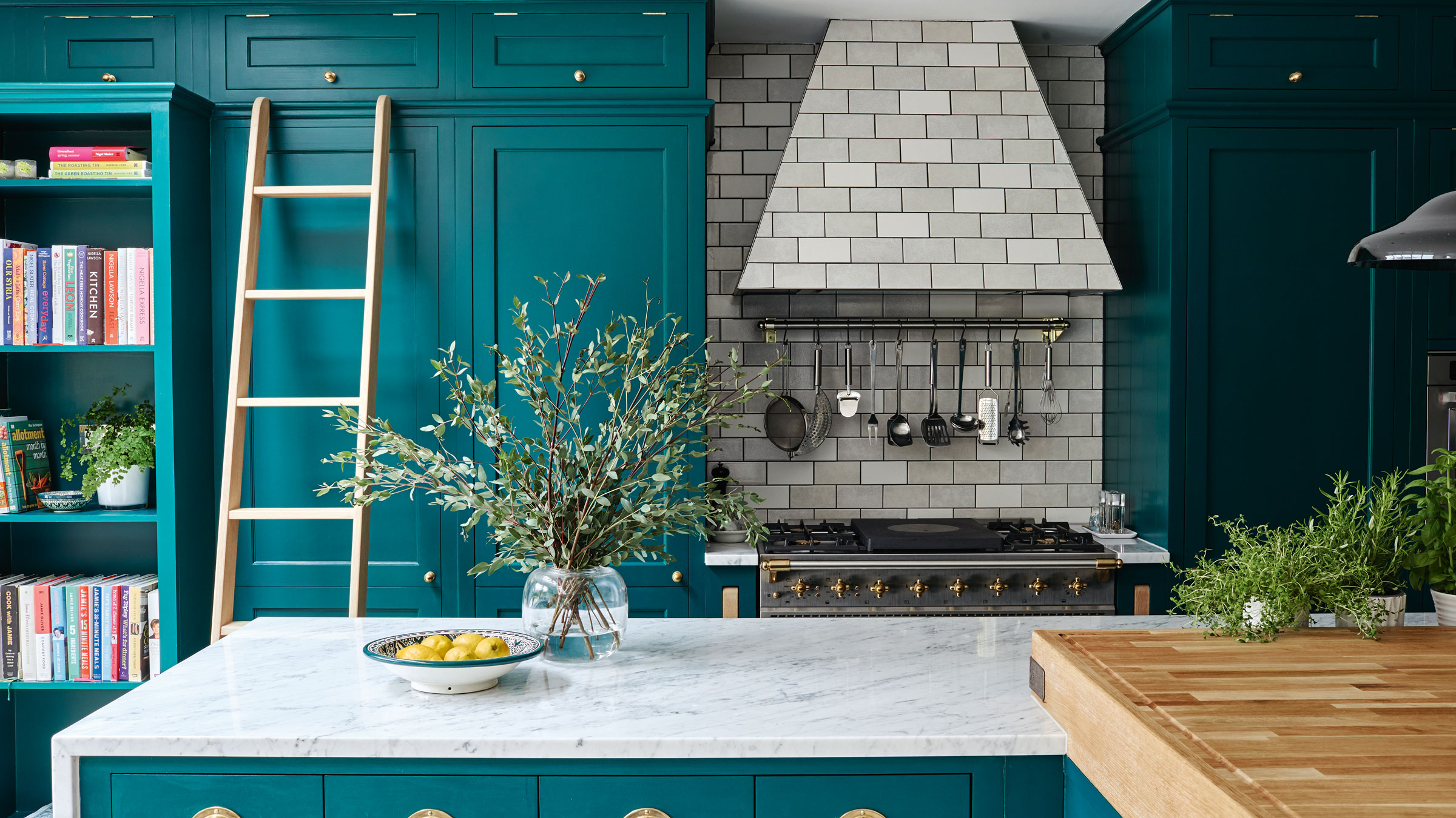 Turquoise kitchen with built in cooker hood and white marble countertop