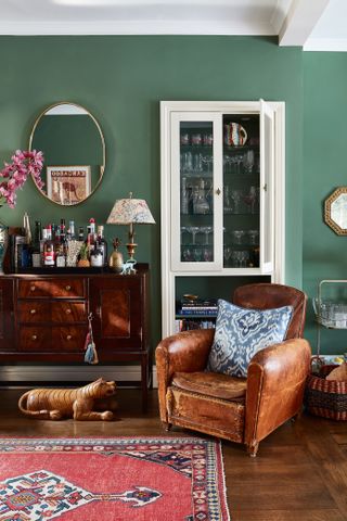living room with green walls leather chair and drinks cabinet