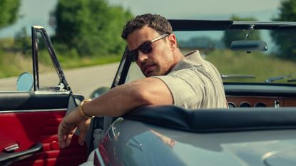 Theo James looks over his shoulder in a convertible