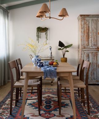 wooden kitchen table with a colorful rug and a blue table runner and vintage accessories