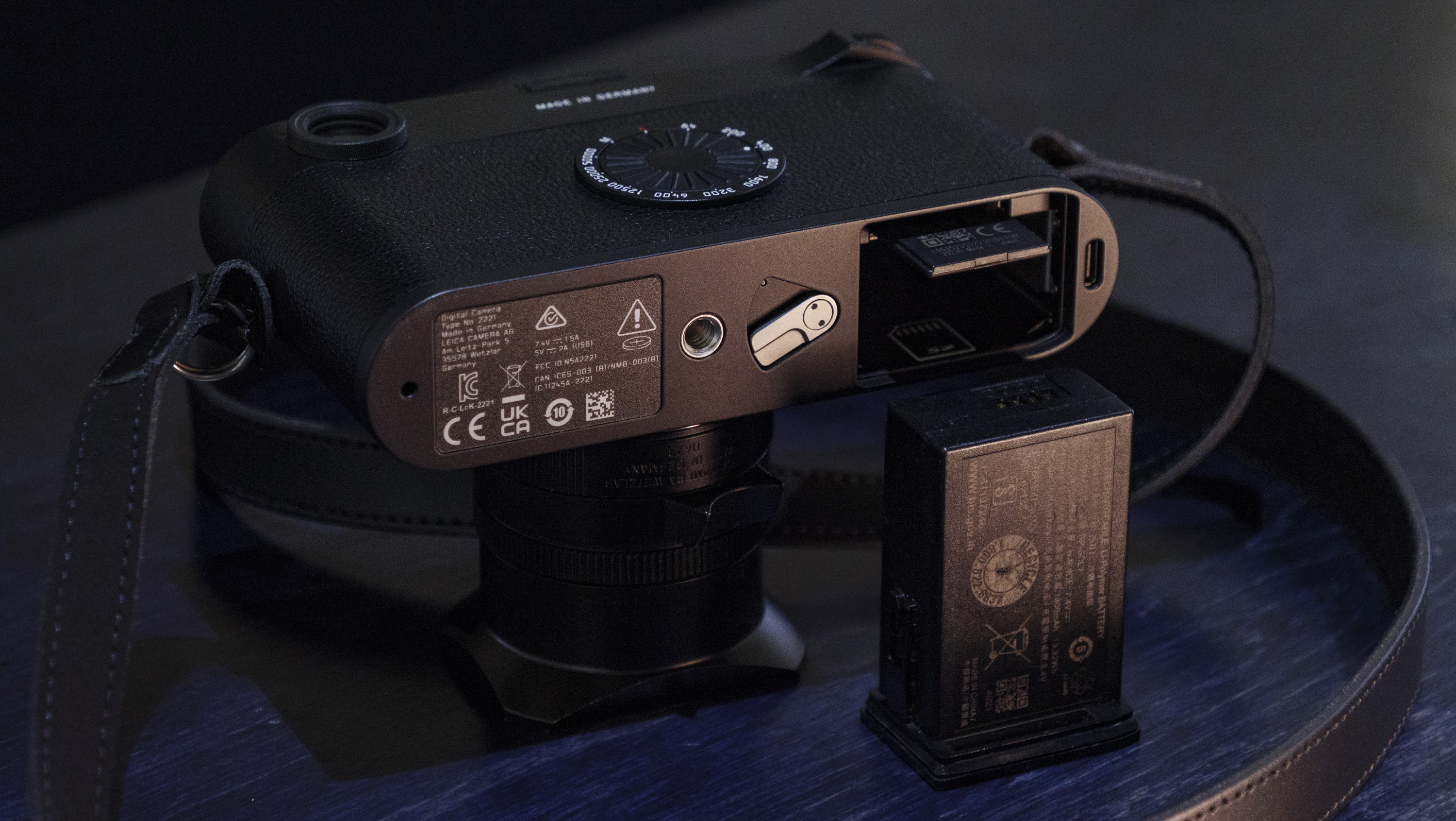 Leica M11-D camera on a dark blue table, low key lighting, close up of battery