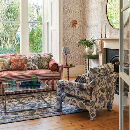 A living room with a striped red and white sofa and floral-print accent chairs matching the rug