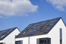 image of a house rooftop with solar panels on it against a blue sky