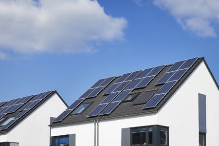 image of a house rooftop with solar panels on it against a blue sky