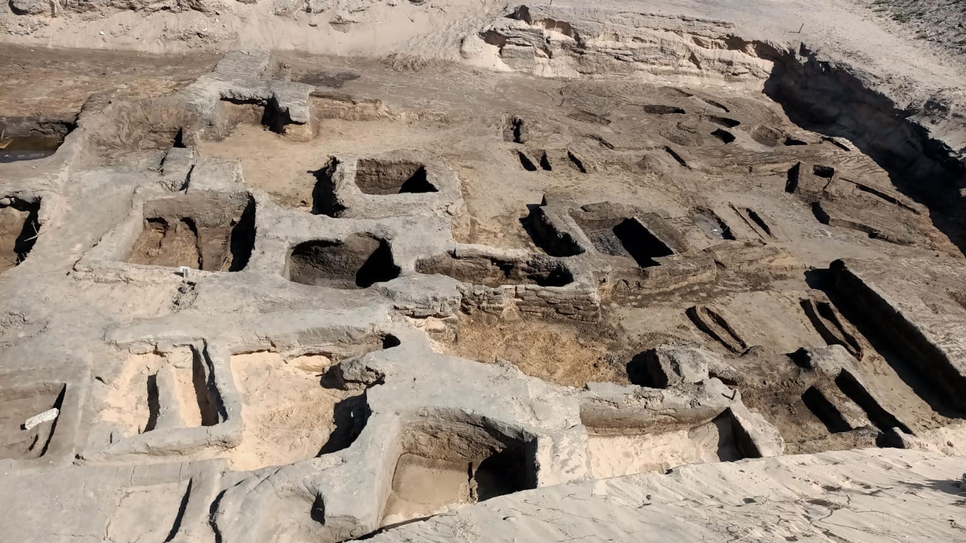 Um sítio de escavação mostrando muitos buracos retangulares no deserto