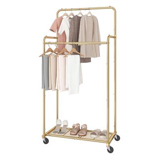 Simple Trending Clothes Rack in brushed gold metal with grate shelf at bottom, two rails of varying height and black wheels