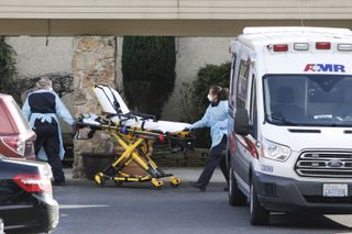 stretcher being wheeled into Life Care Center of Kirkland, Wash., where several cases of COVID-19 have emerged