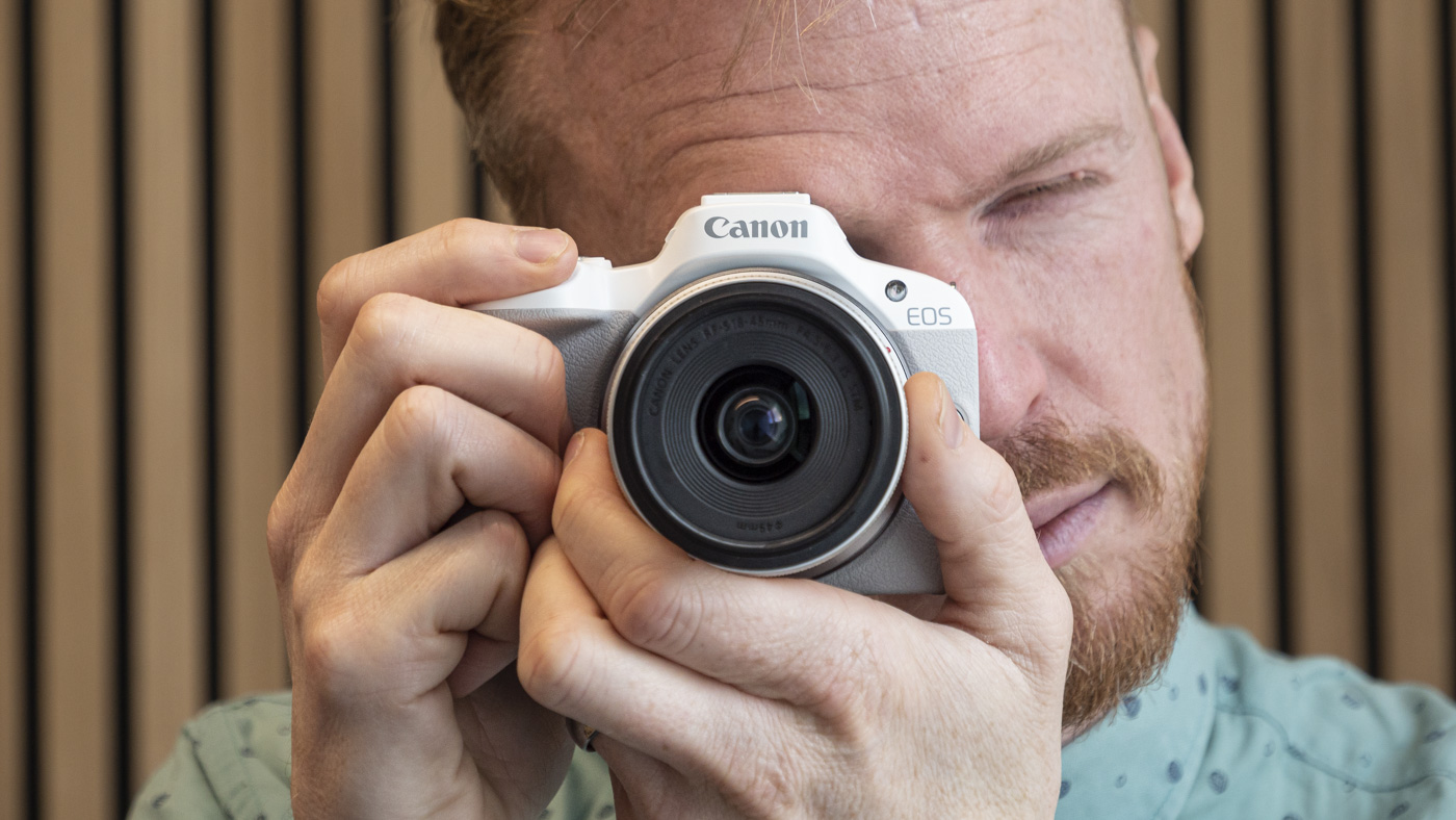 Canon EOS R50 with photographer looking through its viewfinder
