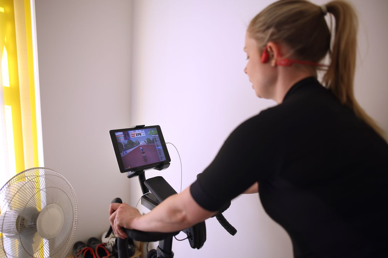 Female cyclist trains on Zwift with a fan in front of her 