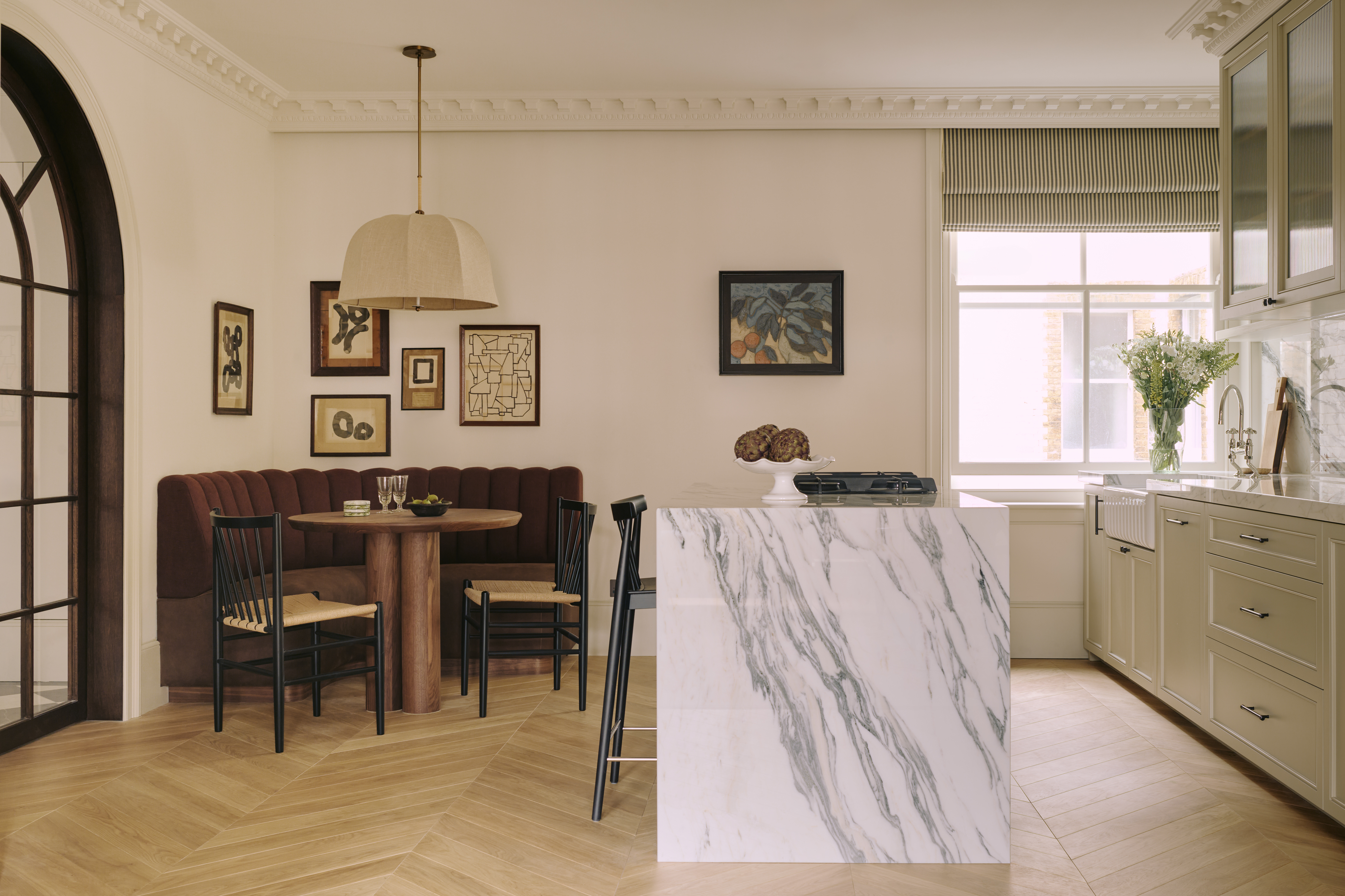 a marble kitchen island in an apartment kitchen with brown banquette seating