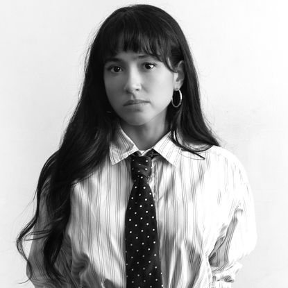 wally baram wears a striped button down and polka dot tie in a black and white posed photo 