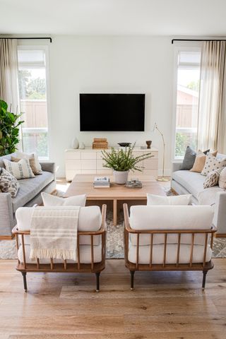 white living room with gray sofas and two armchairs, tv above console, square wood coffee table