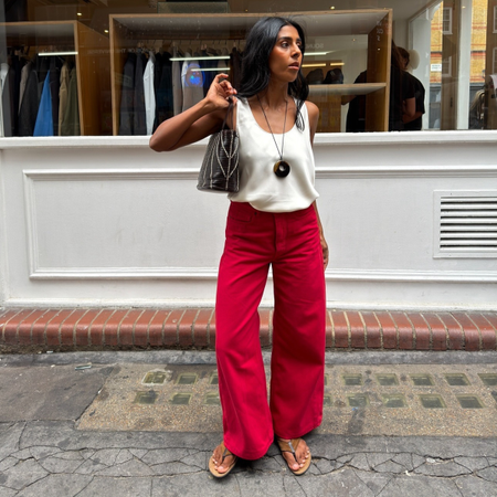 Fashion person Monikh shows how to wear read jeans in 2026. She styles hers with a white satin top, flip-flops and shoulder bag. 