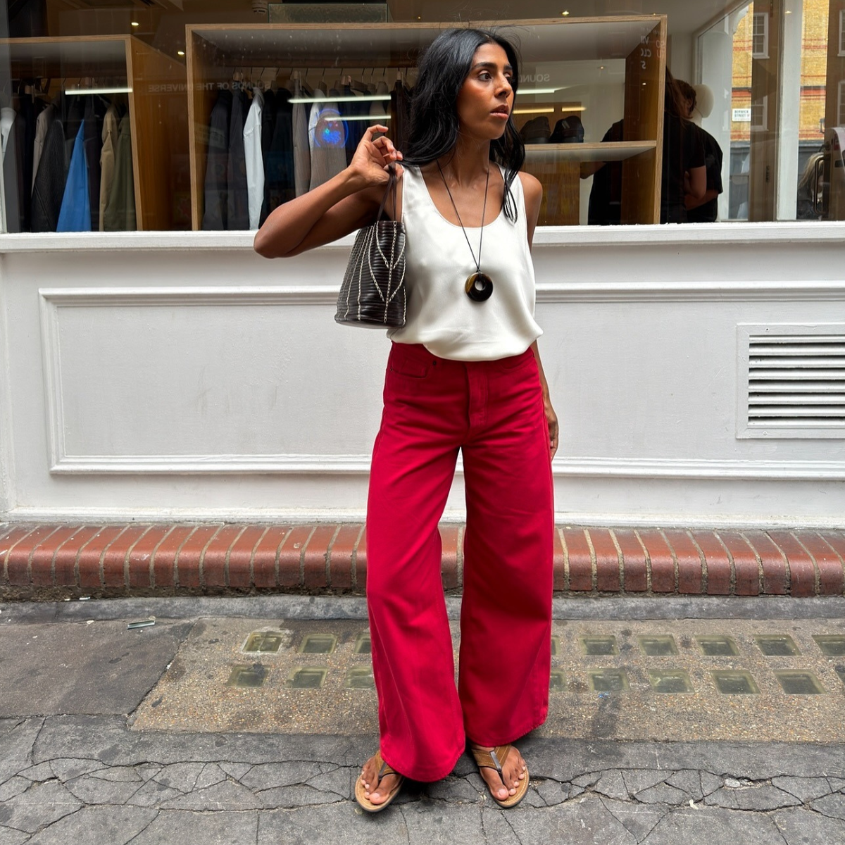 Fashion person Monikh shows how to wear read jeans in 2026. She styles hers with a white satin top, flip-flops and shoulder bag. 