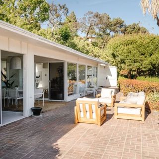 Outdoor living room with white chairs and paved seating area