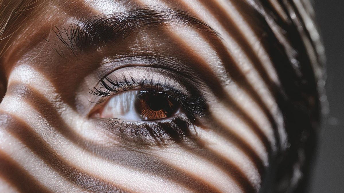 AI generated image of a woman&#039;s eye, with striped shadows from blinds cast across her face