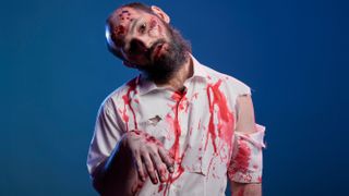 A man dressed as a zombie wearing a white shirt covered in fake blood