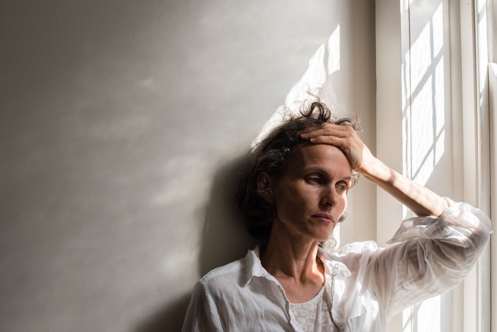Menopause and job loss: A woman looking sad by a window