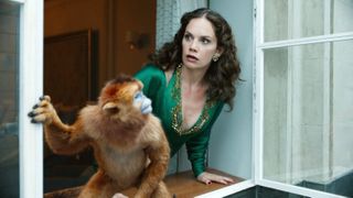 RUTH WILSON looks out a window as a monkey runs away in a still from the tv show his dark materials