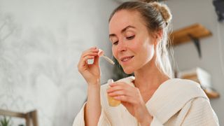 woman using serum from bottle