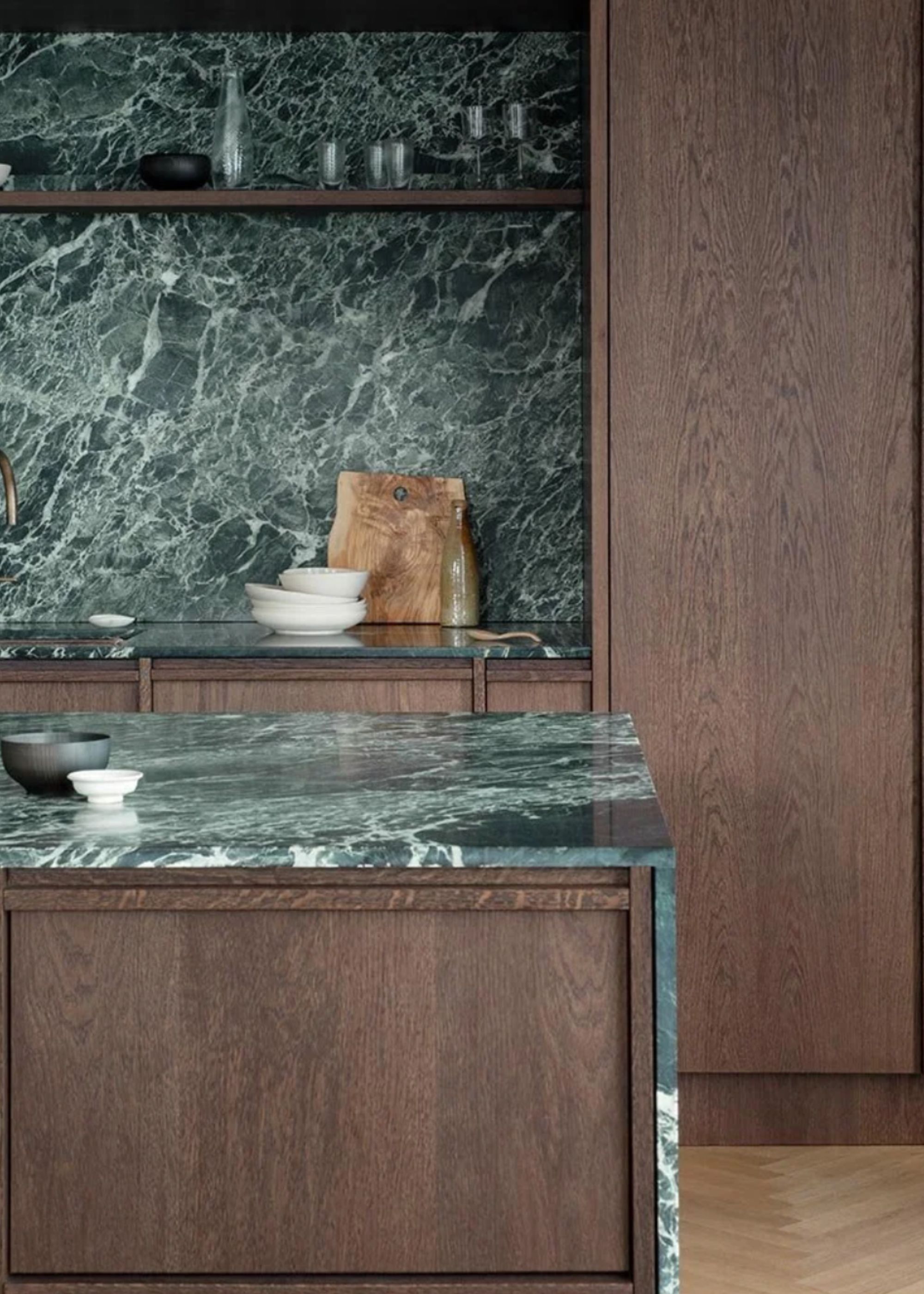 A kitchen with dark green countertop and backsplash in veined marble