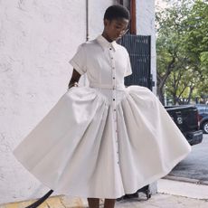 A woman wearing a white summer dress available at Bergdorf Goodman