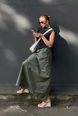 a photo of a woman wearing minimalist wedge sandals with a maxi cargo skirt and sweater