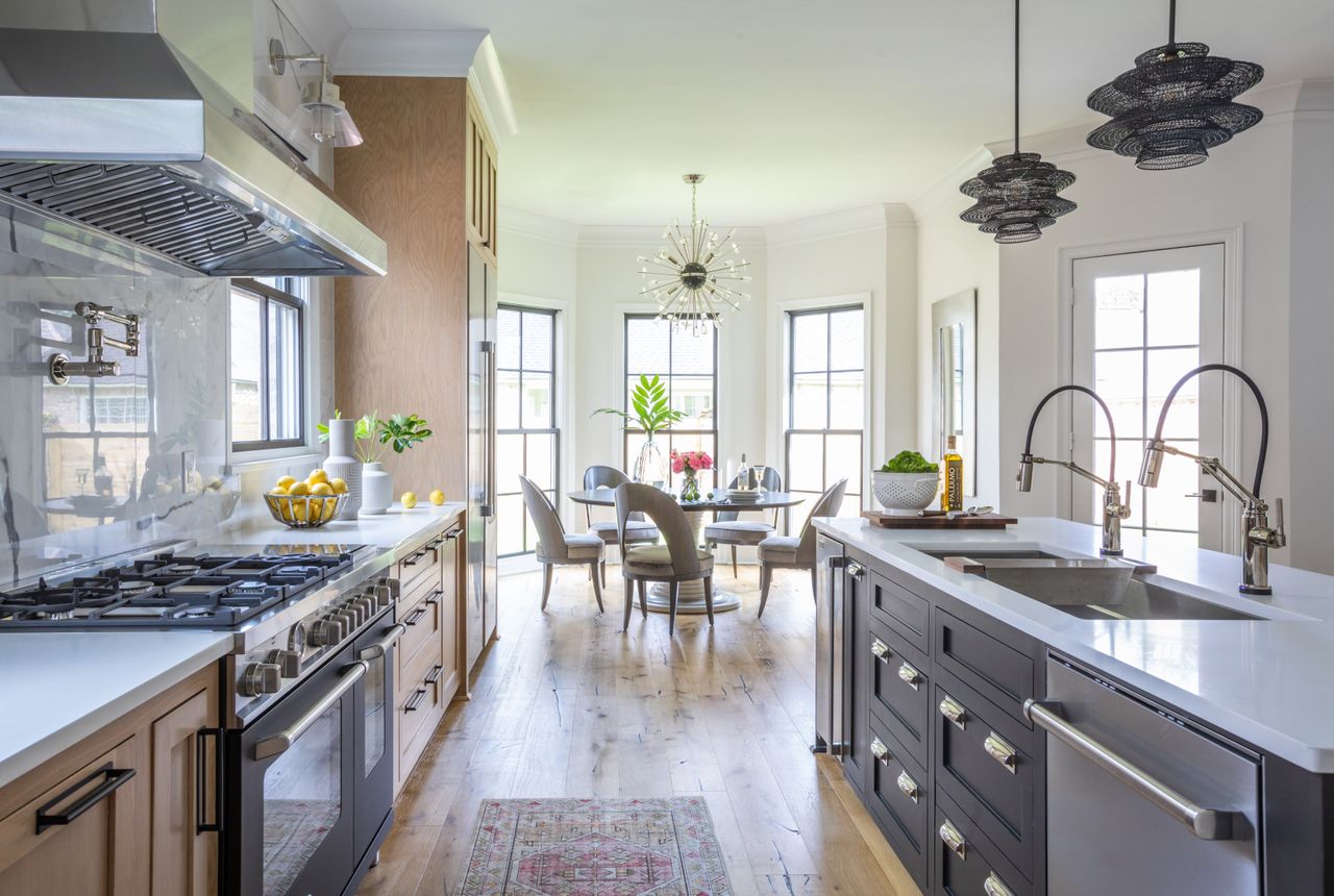 A kitchen with gray cabinetry, a double sink, a large range oven and wooden floors