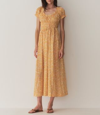 seorang model mengenakan gaun midi lengan pendek bermotif bunga berwarna kuning 