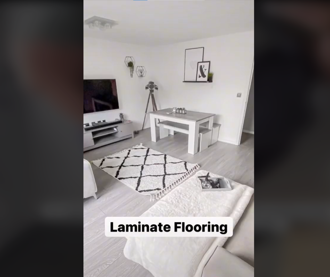 White DIY laminate flooring in living room with a small carpet lying on top